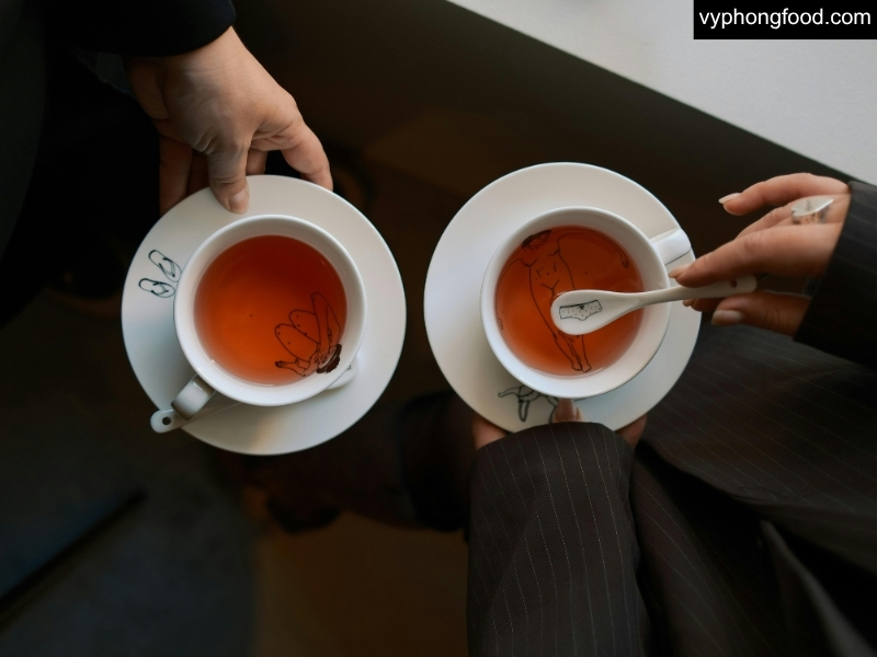 người đang thưởng thức tách hồng trà rooibos african dawn nhập khẩu chính ngạch từ nam phi sau bữa ăn giúp hỗ trợ chức năng gan khỏe mạnh và giảm căng thẳng chuyển hóa